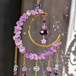 Close-up of a gold crescent frame with purple stone beads, glass accents and a flower charm