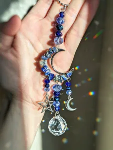 Dettaglio di perline blu sfaccettate, luna e stella argentate e sfera di cristallo