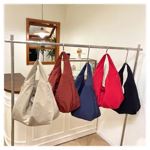 Fünf leichte Schultertaschen mit Knitteroptik in Beige, Rostrot, Navy, Rot und Schwarz am Ständer
