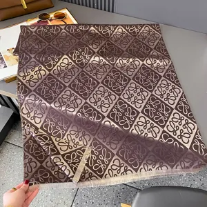 Flach ausgelegter brauner Jacquardschal mit wiederholtem Schleifenmuster und hellen Fransen