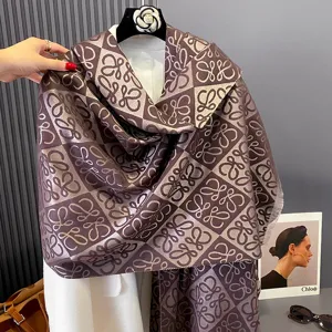 Drapierter Schal mit lila-braunen und beigen geometrischen Motiven und weichen Fransen am Rand