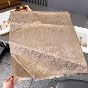 Flach ausgelegter taupefarbener Jacquard-Schal mit wiederholtem Muster und Fransen an den Kanten