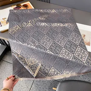 Schal mit geometrischem Jacquardmuster in Graubraun, flach ausgelegt und mit Fransen