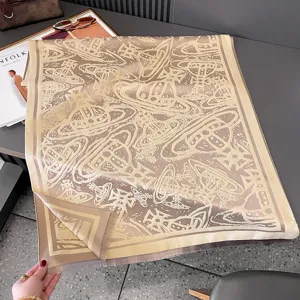 Flach ausgelegtes Tuch in Beige und Taupe mit umlaufendem Planetenmotiv und Fransenrand