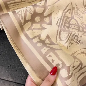 Detail eines warmen Beige-Camel-Schals mit Retroornamenten, Jacquardstruktur und genähtem Rand