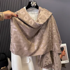Stola jacquard tortora su manichino, con dettagli ravvicinati dei motivi a cuore e leopardo