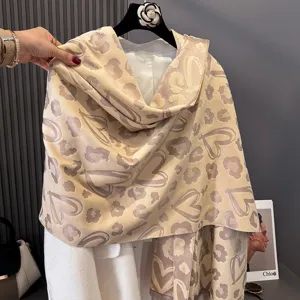 Dettaglio di una sciarpa beige appesa, con macchie leopardate e motivi decorativi a cuore