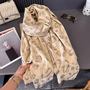 Sciarpa lunga beige con motivi a cuore leopardati e bordi sfrangiati, mostrata distesa