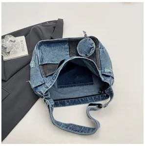 Top view of an open patchwork denim bag showing its dark interior, round coin pouch and strap