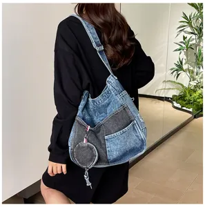Model wearing a blue and charcoal denim patchwork bag with a round plush coin purse charm