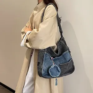 Washed denim shoulder bag in gray and blue patchwork with distressed details and a round charm