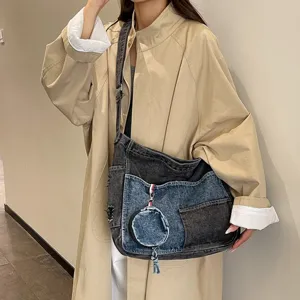 Patchwork denim shoulder bag in charcoal and washed blue, worn crossbody with round coin pouch