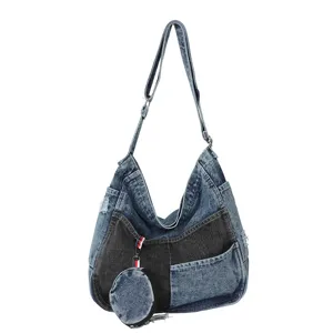 Blue denim shoulder bag with black patchwork, distressed details, adjustable strap and coin pouch
