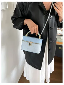 Una modella porta una borsa azzurro chiaro con stelle e catena dorata, sopra abiti scuri