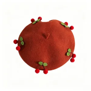 Brick-red wool beret with red pom-pom cherries and green leaves, viewed from above