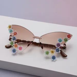 Close-up of brown gradient lenses with colorful glitter flower accents on rimless sunglasses