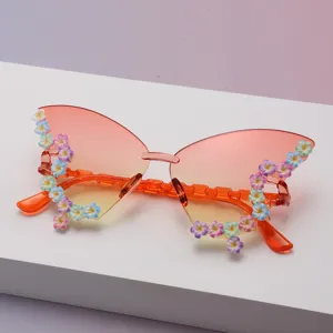 Randlose Schmetterlingsbrille mit orangefarbenen Verlaufsgläsern und bunten Blüten an den Bügeln