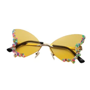 Lunettes de soleil papillon sans monture, verres jaunes, pont doré et détails colorés sur les bords