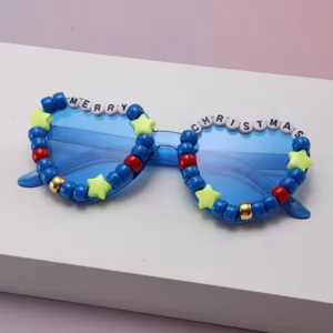 Close-up of blue sunglasses with beaded frames spelling “Merry Christmas” and star accents
