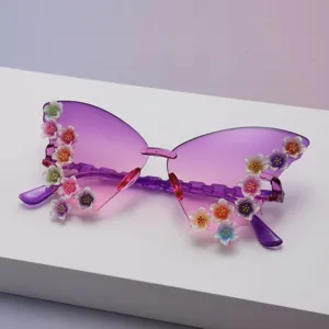 Close-up of glittery floral accents on purple butterfly sunglasses with pink-gradient lenses