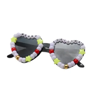 Heart-shaped sunglasses with black frames, dark gray lenses and colorful Merry Christmas bead trim