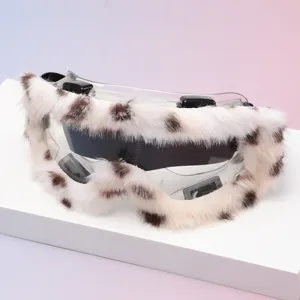 Close-up of clear goggles with white faux-fur trim, brown spots, dark lens and black clips