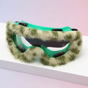Green goggles with shaggy beige faux-fur trim and dark lenses, displayed on a white platform