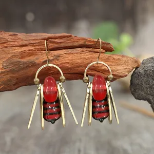 Paire de boucles d’oreilles pendantes rayées rouge et noir, cadre doré, suspendues à une branche