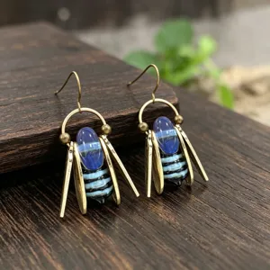Vue rapprochée de perles en verre bleues rayées, avec feuilles dorées et crochets sur bois sombre