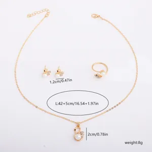 Flat lay of gold-tone swan necklace, earrings and ring with pearl accents and rhinestone wings