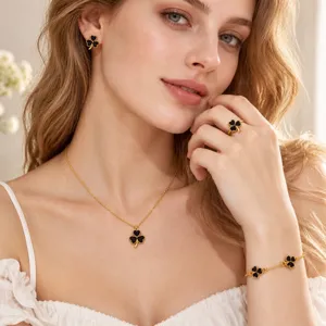 Close-up of a model wearing black four-leaf clover jewelry with gold-tone details