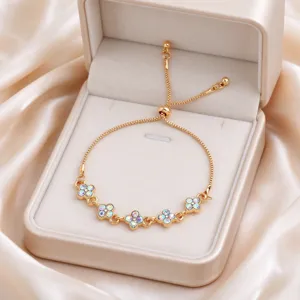 Gold bracelet with five iridescent flower clusters and adjustable slider clasp in a jewelry box