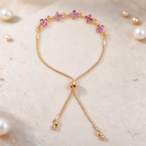 Close-up of pink flower stones on a gold bracelet with an adjustable sliding clasp