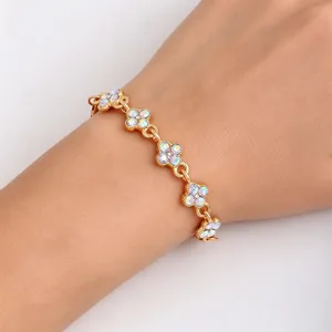 Close-up of a gold-tone bracelet with crystal flower links worn on the wrist in soft light