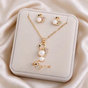 Gold-tone swan necklace, earrings, and ring with pearl and crystal accents on a jewelry display