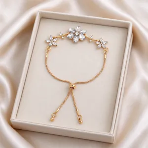 Detail of crystal flower accents, gold-tone chain and adjustable slider clasp in a jewelry box