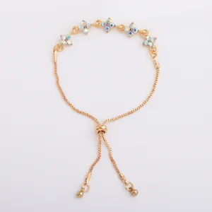Detail of a gold-tone bracelet with iridescent four-petal flower charms and a sliding clasp