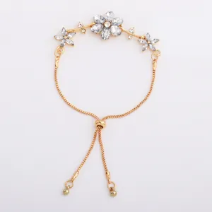 Flat lay showing a gold-tone adjustable bracelet with clear crystal flower and branch decorations