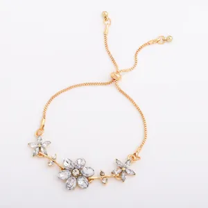 Gold-tone sliding chain bracelet with three clear crystal flowers, shown flat on white