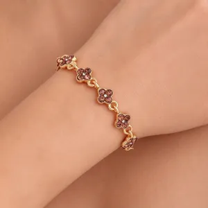 Close-up of a gold-tone flower-link bracelet with brown crystals worn around the wrist
