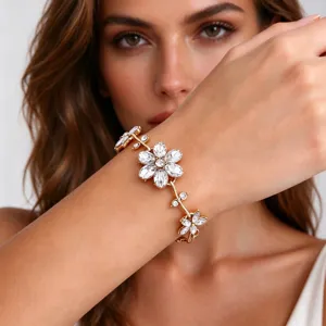 Close-up of a gold-tone floral bracelet with clear crystal petals worn on the wrist in soft light