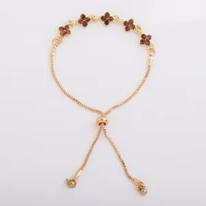 Gold-tone bracelet displayed flat, with five brown crystal flower motifs and adjustable slider clasp