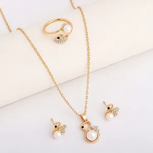 Gold-tone swan-shaped pieces with pearl and crystal accents arranged on a pale display surface.