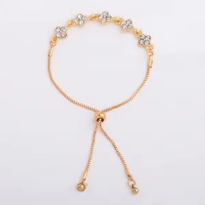 Detail of a gold-tone bracelet with five four-petal crystal flowers and an adjustable slider clasp