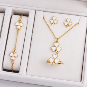 White clover jewelry pieces with gold-tone settings arranged neatly in a soft white display box
