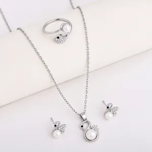 Flat lay of silver-tone swan jewelry with white pearl and crystal accents on a light surface