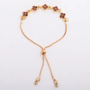 Gold-tone bracelet laid flat, showing brown four-petal flower links and an adjustable sliding clasp