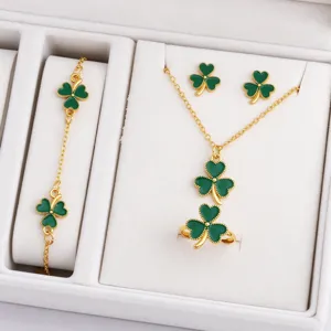 Four-piece gold-tone jewelry set with green clover motifs in a white velvet display box