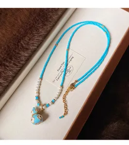 Collana di perline turchesi con dettagli perlati e ciondolo a zucca smaltato con bordo dorato