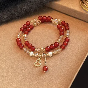 Dettaglio di perle rosse, cristalli sfaccettati, accenti perlati e ciondolo dorato a forma di zucca